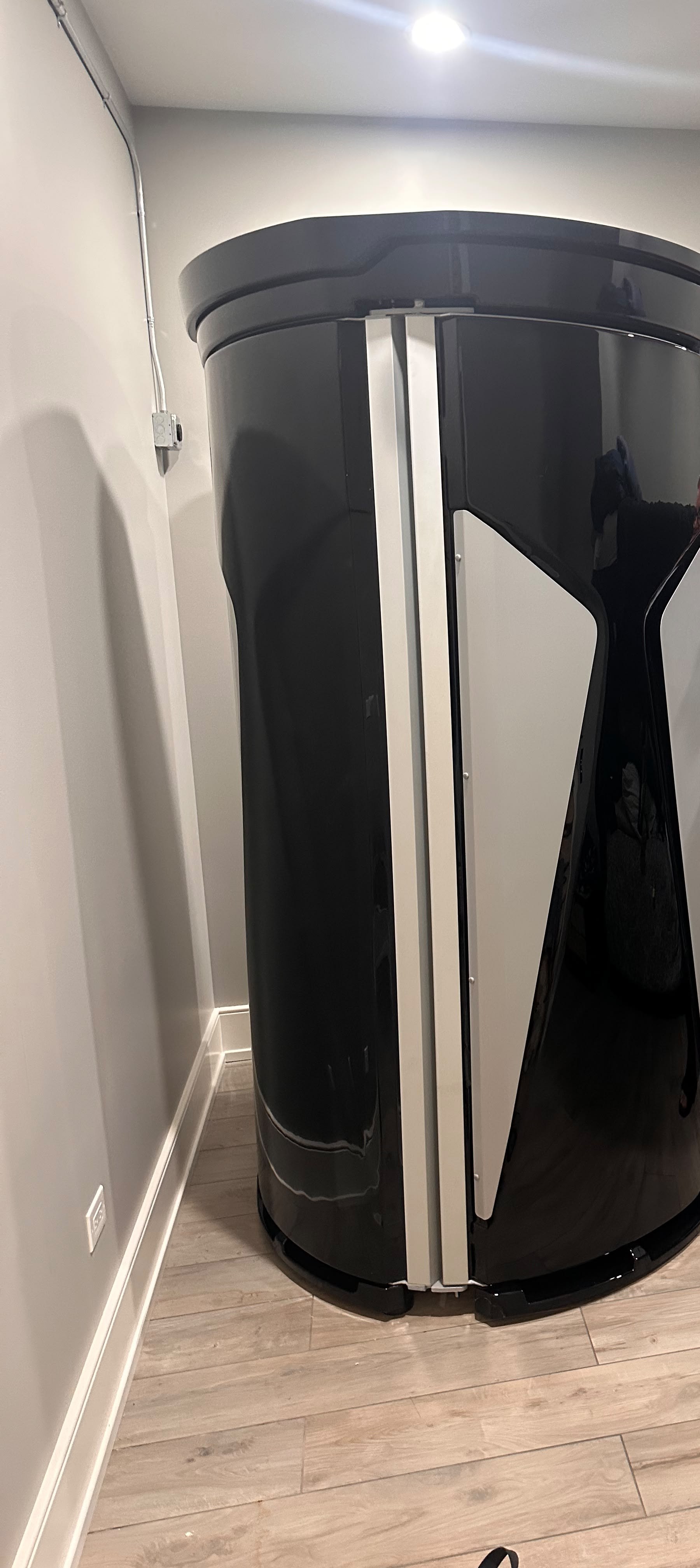 A tall standalone light booth placed along one side of a private wellness room; customer identifying details are outside the crop
